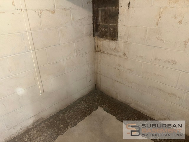 Water stained basement wall with concrete removed along the footing to prepare the drain tile trench in Southeastern Michigan