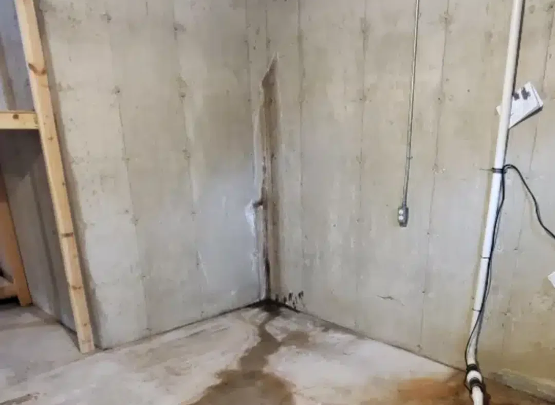 Leaking crack running down the corner of a poured concrete basement wall in Southeast Michigan