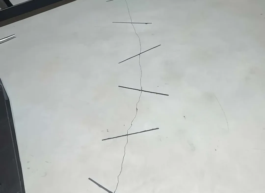 Finished carbon fiber staple stitching across a cracked basement floor in Attica, Michigan
