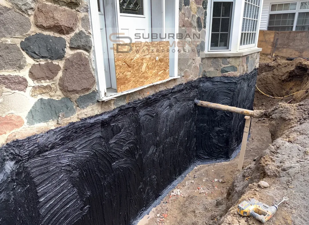 Exterior foundation waterproofing tar coating on a stone foundation in Franklin, Michigan