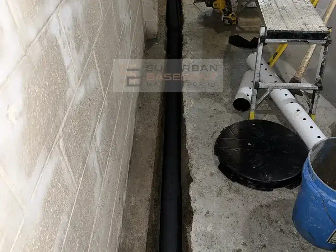 Perforated drain tile in a black sediment sleeve dry fitted in a trench along a basement footing in Ferndale MI