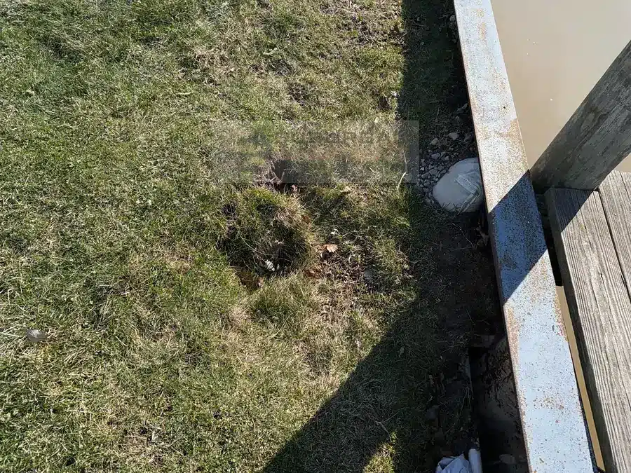 Eroded voids and soft spots in a lawn along a canal seawall in Harrison Township MI