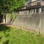 Cracked poured concrete retaining wall with a wood railing in Farmington Hills MI before repair