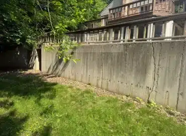 Cracked poured concrete retaining wall with a wood railing in Farmington Hills MI before repair