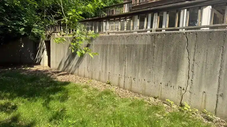 Cracked poured concrete retaining wall with a wood railing in Farmington Hills MI before repair