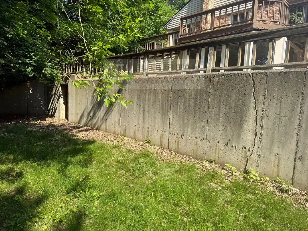 Cracked poured concrete retaining wall with a wood railing in Farmington Hills MI before repair