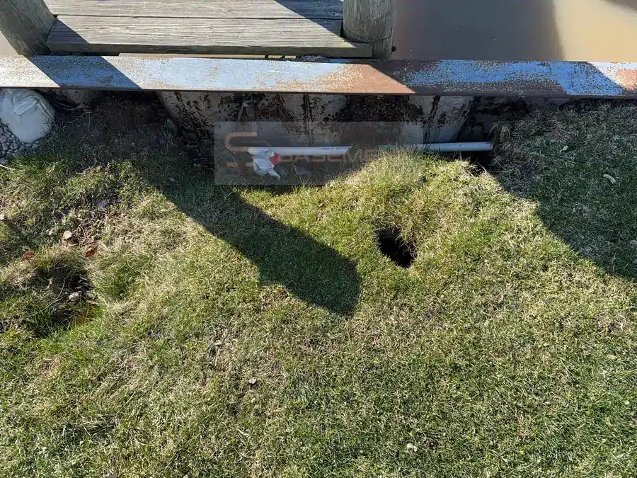 Open sinkhole in a lawn beside a canal seawall in Harrison Township MI before repair