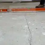 Level across a cracked, settled condo living room concrete slab in Troy MI before void filling and concrete leveling